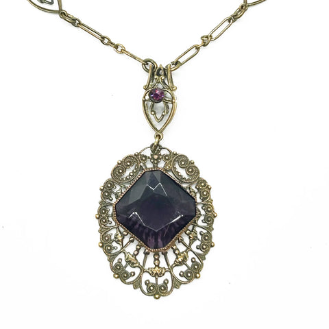 Enhance your jewelry collection with this one-of-a-kind standout piece. Adorned with intricate filigree and glistening purple stones, this necklace exudes elegance and charm. The centerpiece, a stunning diamond-shaped violet stone set in an ornate oval frame, adds a touch of luxury to any outfit