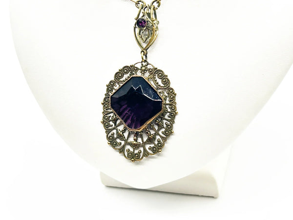 Enhance your jewelry collection with this one-of-a-kind standout piece. Adorned with intricate filigree and glistening purple stones, this necklace exudes elegance and charm. The centerpiece, a stunning diamond-shaped violet stone set in an ornate oval frame, adds a touch of luxury to any outfit
