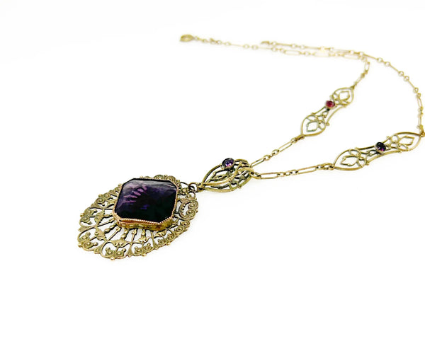 Enhance your jewelry collection with this one-of-a-kind standout piece. Adorned with intricate filigree and glistening purple stones, this necklace exudes elegance and charm. The centerpiece, a stunning diamond-shaped violet stone set in an ornate oval frame, adds a touch of luxury to any outfit