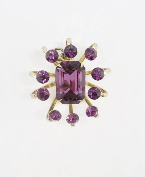 Be captivated by this stunning vintage pendant, boasting a dazzling golden toned abstract floral design and an eye-catching emerald cut stone. The intricate curling petals and rich purple round stones add another level of charm to this timeless piece, measuring 1 ¼” similar to a sought-after signed Coro piece.
