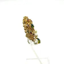 Product photo of a vintage antique-gold filigree pin. The central oval frame holds bright green and red glass gems. Six small dangling charms hang from the bottom, including five creamy white pearls and one round green rhinestone.