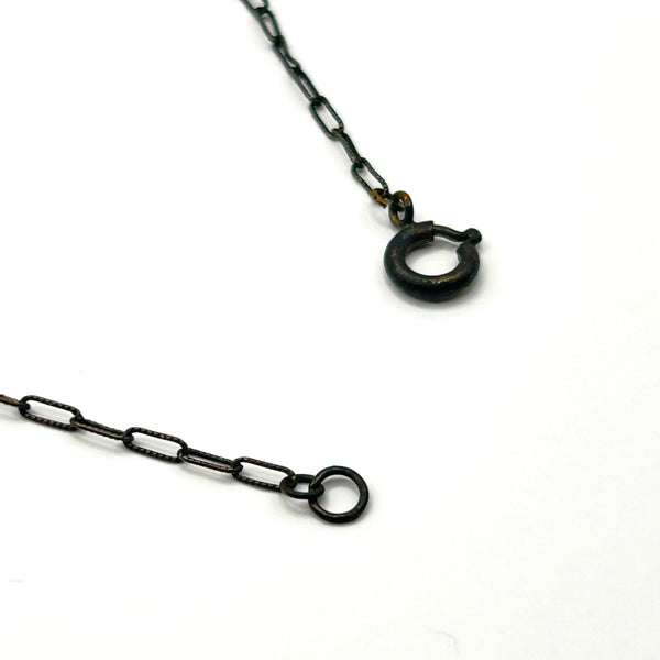 A vintage necklace featuring clusters of deep purple bicone crystal beads on a dark-toned paperclip chain, culminating in a large, heavily faceted diamond-shaped purple crystal drop pendant