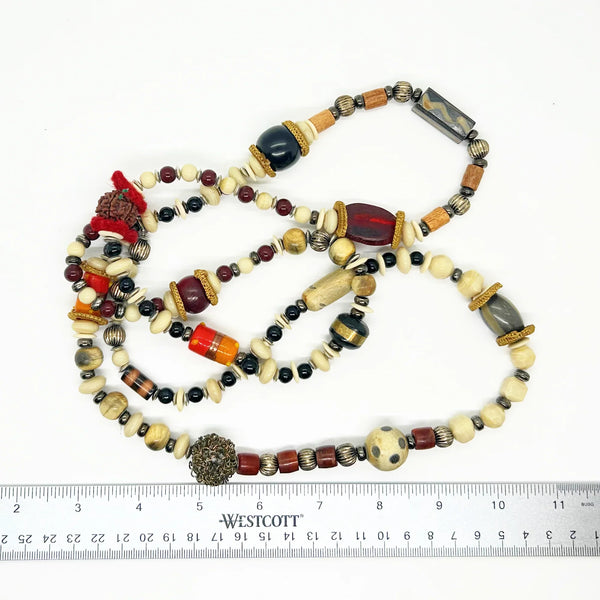 This captivating necklace is a true statement piece, boasting a unique blend of beads in an array of shapes and sizes. The earthy, nature-inspired hues create a stunning visual, with warm tones of red, black, and cream that beautifully coordinate with any fall ensemble. At nearly 60 inches in length, this adaptable infinity necklace is designed without a clasp, providing endless styling possibilities.