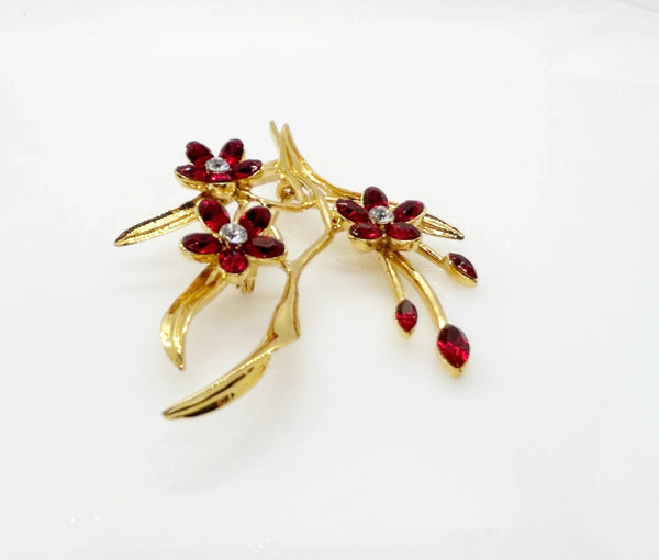 This vintage floral pin will add glamour- three blooms are exquisitely crafted of deep red marquise stones, complemented by a glistening clear rhinestone in the center. This gorgeous piece is in excellent condition and measures 3.25" tall.