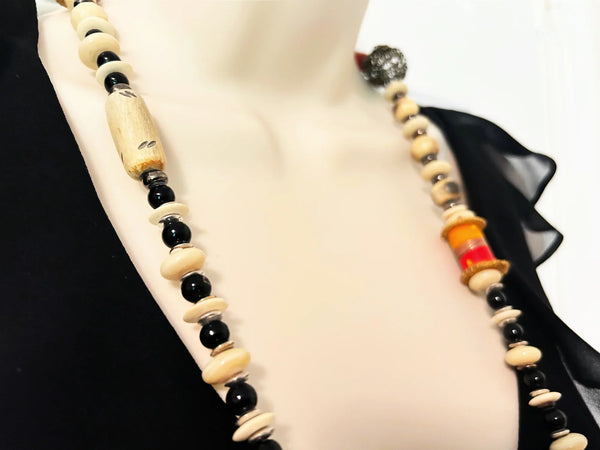 This captivating necklace is a true statement piece, boasting a unique blend of beads in an array of shapes and sizes. The earthy, nature-inspired hues create a stunning visual, with warm tones of red, black, and cream that beautifully coordinate with any fall ensemble. At nearly 60 inches in length, this adaptable infinity necklace is designed without a clasp, providing endless styling possibilities.