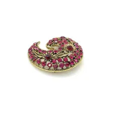 Close-up detail of a mid-century paisley swirl pin showing the openwork metal vines and prong-set pink and red rhinestone crystals