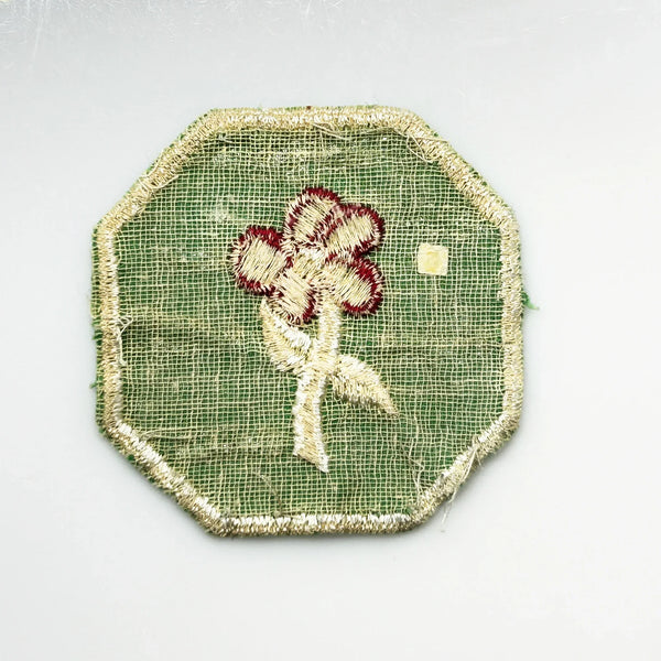 This is a vintage Girl Scout troop crest patch, featuring a red flower design with a white center and stem on a green octagonal background. This specific design has been retired. It depicts either a Scarlet Pimpernel or a Cardinal Flower, with the specific name depending on the era it was produced.