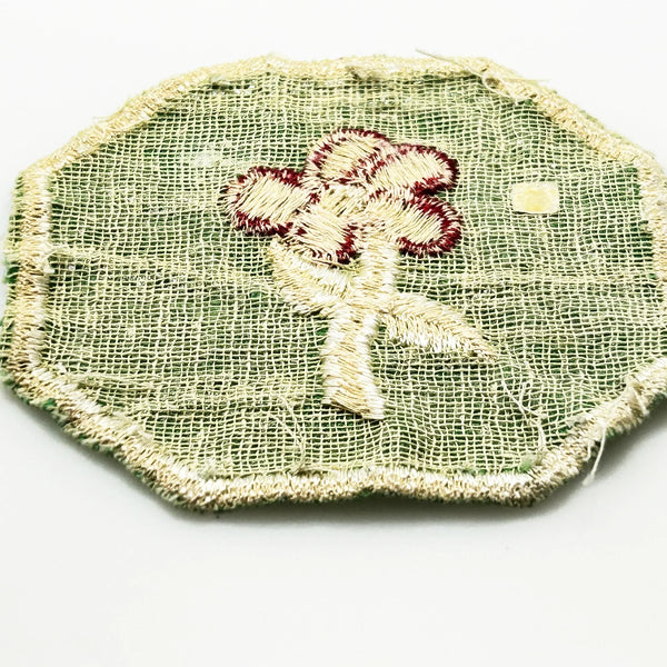 This is a vintage Girl Scout troop crest patch, featuring a red flower design with a white center and stem on a green octagonal background. This specific design has been retired. It depicts either a Scarlet Pimpernel or a Cardinal Flower, with the specific name depending on the era it was produced.