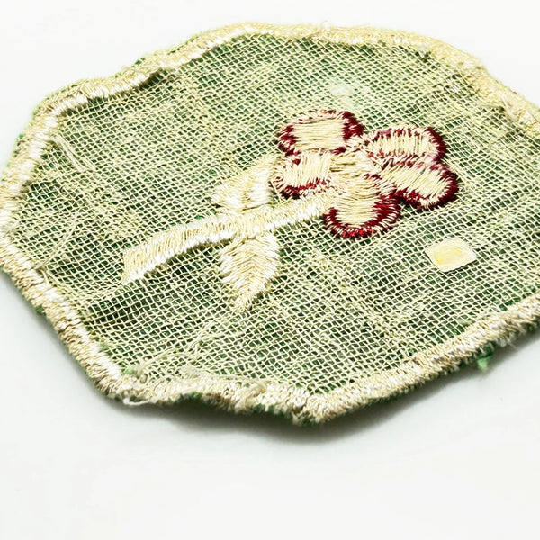 This is a vintage Girl Scout troop crest patch, featuring a red flower design with a white center and stem on a green octagonal background. This specific design has been retired. It depicts either a Scarlet Pimpernel or a Cardinal Flower, with the specific name depending on the era 