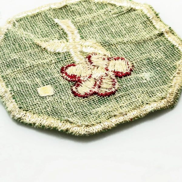 This is a vintage Girl Scout troop crest patch, featuring a red flower design with a white center and stem on a green octagonal background. This specific design has been retired. It depicts either a Scarlet Pimpernel or a Cardinal Flower, with the specific name depending on the era 