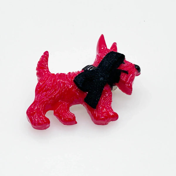 Adopt this captivating and unusual Scottie Dog Brooch, crafted in a bold red hue with a lavish black ribbon bow adorning its neck. Measuring 1.25" in width, it is in impeccable condition. His black collar and nose complete the look. 