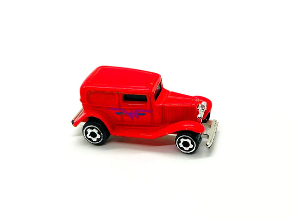 A red vintage toy car with black and white wheels and a small silver front bumper, photographed on a plain white background.