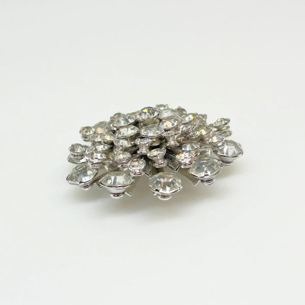 This extraordinary vintage rhinestone brooch features several layers of brilliant, round, sparking stones of varying sizes, measuring 2" across. The back of the brooch is stunning, showcasing exquisite metalwork and reflecting its excellent condition.