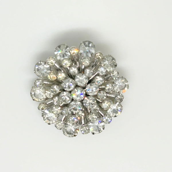 This extraordinary vintage rhinestone brooch features several layers of brilliant, round, sparking stones of varying sizes, measuring 2" across. The back of the brooch is stunning, showcasing exquisite metalwork and reflecting its excellent condition.