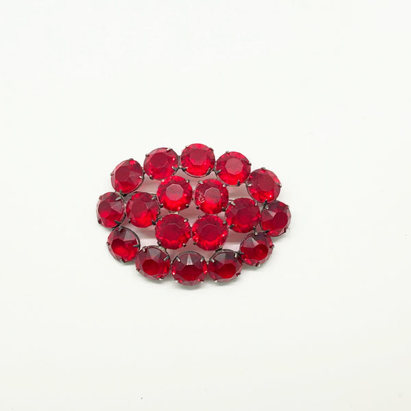 A cluster of round-cut red rhinestones arranged in a small oval cluster on a plain white background.