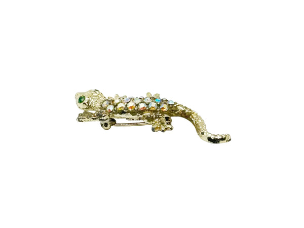 This enchanting vintage salamander brooch captures the magic of mid-century costume jewelry with its shimmering Aurora Borealis rhinestones and lustrous gold-toned setting. The iridescent body gleams with multi-colored stones that shift and dance in the light, while striking green accents highlight the creature's expressive eyes.