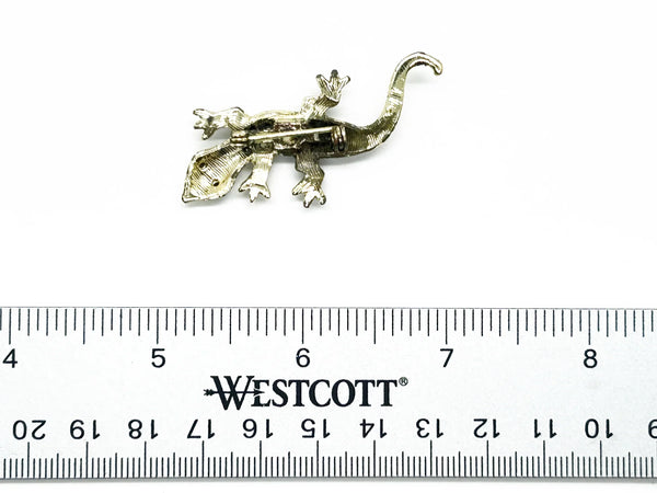 This enchanting vintage salamander brooch captures the magic of mid-century costume jewelry with its shimmering Aurora Borealis rhinestones and lustrous gold-toned setting. The iridescent body gleams with multi-colored stones that shift and dance in the light, while striking green accents highlight the creature's expressive eyes.