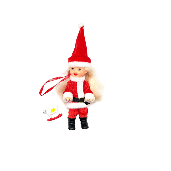 Vintage 2003 Mattel Barbie Kelly Club Santa Claus Christmas ornament doll. The miniature blonde doll is dressed in a red and white Santa suit with black boots, featuring a built-in red ribbon hanger and a small holiday candle accessory against a white background