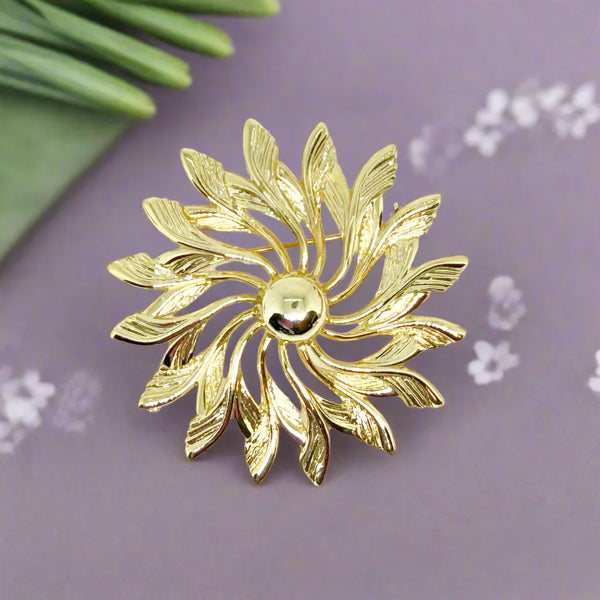 Celebrate timeless elegance with this Sarah Coventry Gold Tone Sunburst Flower Brooch. Featuring a beautifully textured gold-tone design, this vintage piece captures the radiant energy of a blossoming flower or a glowing sunburst.