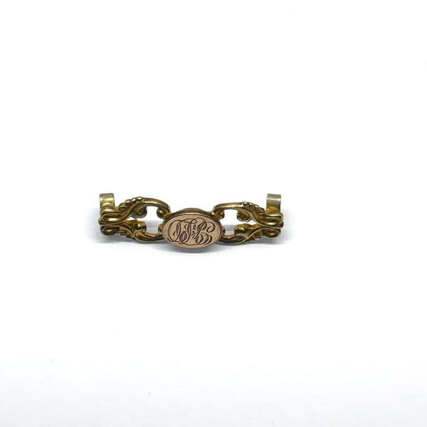Antique Victorian monogrammed watch slide in gold-tone metal. Features a round hand-engraved monogram center and highly detailed repoussé scrollwork side accents, perfect as a jewelry making component