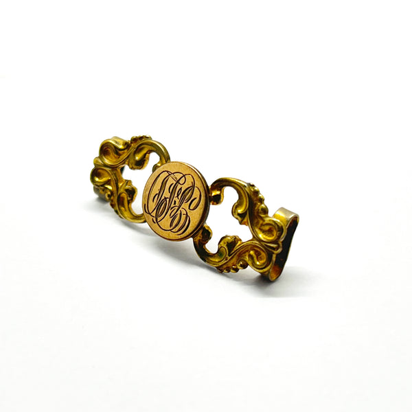 Antique Victorian monogrammed watch slide in gold-tone metal. Features a round hand-engraved monogram center and highly detailed repoussé scrollwork side accents, perfect as a jewelry making component