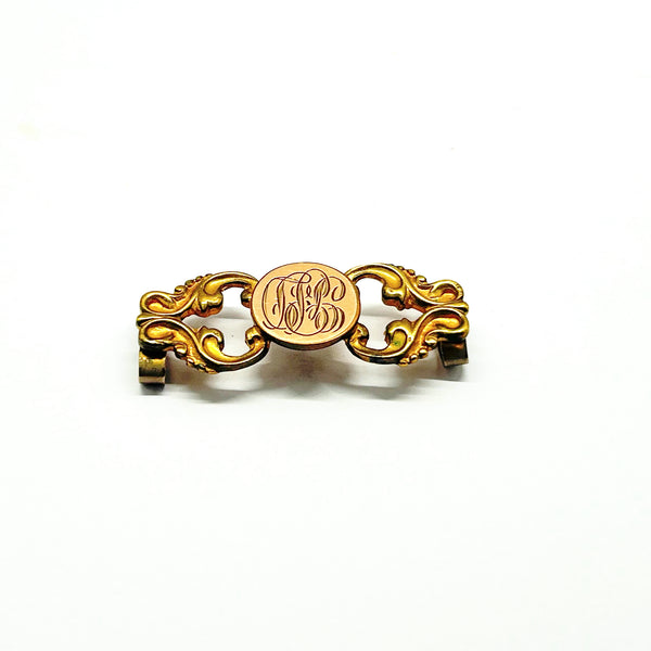 Antique Victorian monogrammed watch slide in gold-tone metal. Features a round hand-engraved monogram center and highly detailed repoussé scrollwork side accents, perfect as a jewelry making component