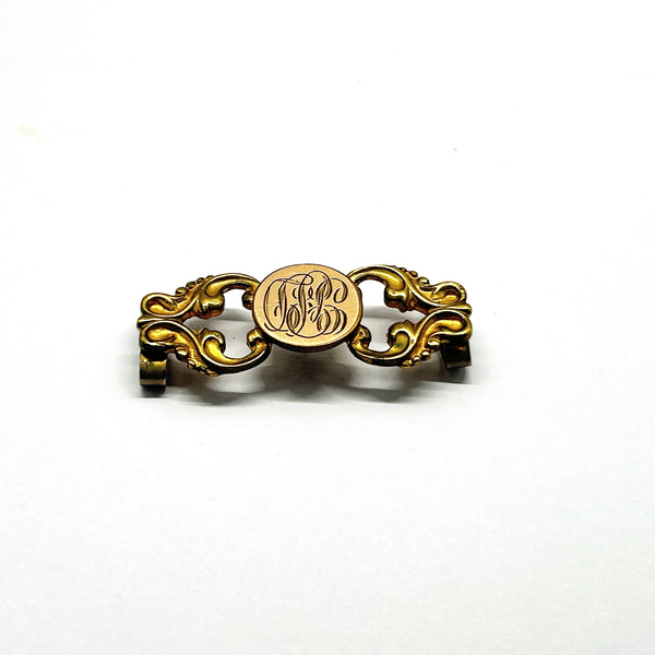 Antique Victorian monogrammed watch slide in gold-tone metal. Features a round hand-engraved monogram center and highly detailed repoussé scrollwork side accents, perfect as a jewelry making component