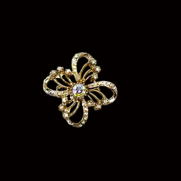This is a three dimensional vintage ribbon brooch featuring clear rhinestones and a central aurora borealis (AB) gemstone, designed in an abstract floral or bow shape. 