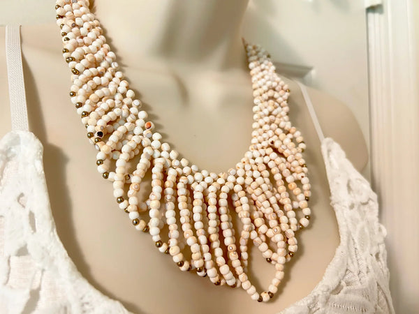 This elaborate vintage necklace showcases delicate loops of the softest light pink beads, beautifully accented with tiny gold beads that add a subtle shimmer. Secured with a classic barrel clasp, it measures 18" in length and gracefully drapes 3" at its longest point, creating a stunning layered effect. Despite its dramatic appearance, 
