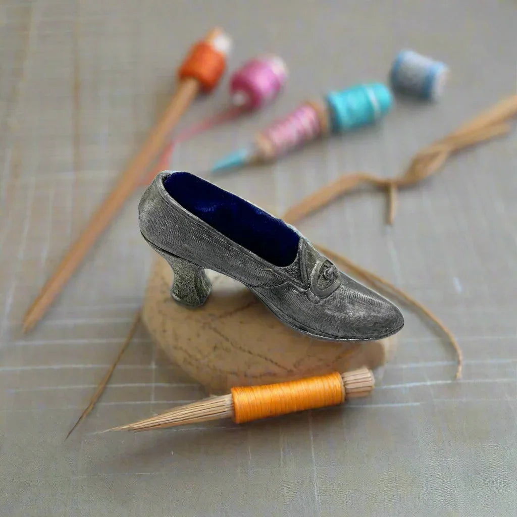 This dainty vintage pincushion is just the thing the add a unique touch to your surroundings. It is made of pewter in the shape of a shoe, with a classic loafer type detail at the toe. It has a .75" kitten heel, and the insole is filled with dark blue, midnight velvet.