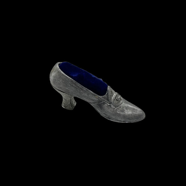 This dainty vintage pincushion is just the thing the add a unique touch to your surroundings. It is made of pewter in the shape of a shoe, with a classic loafer type detail at the toe. It has a .75" kitten heel, and the insole is filled with dark blue, midnight velvet.