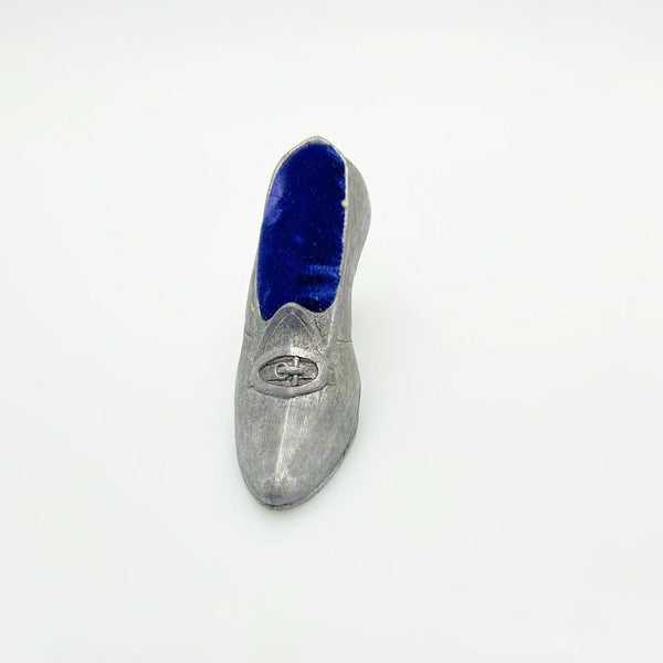 This dainty vintage pincushion is just the thing the add a unique touch to your surroundings. It is made of pewter in the shape of a shoe, with a classic loafer type detail at the toe. It has a .75" kitten heel, and the insole is filled with dark blue, midnight velvet.