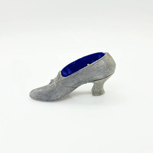 This dainty vintage pincushion is just the thing the add a unique touch to your surroundings. It is made of pewter in the shape of a shoe, with a classic loafer type detail at the toe. It has a .75" kitten heel, and the insole is filled with dark blue, midnight velvet.