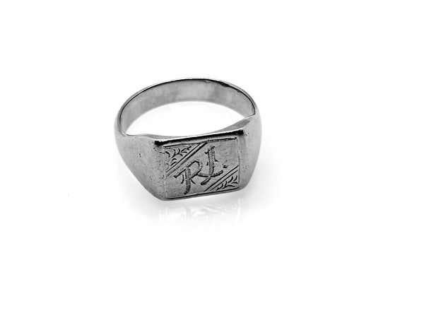 A silver-toned signet ring with engraved initials 'RJ' on a polished rectangular face, shown on a clean white background with a soft reflection.