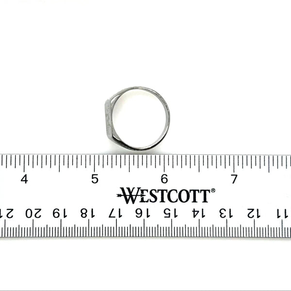 Silver ring next to a Westcott ruler on a white background