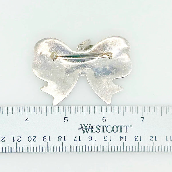 Experience the elegance of our Vintage Sterling Silver Bow Pendant/Brooch. Featuring a beautifully puffed, hollow design, this accessory brings refined style to your wardrobe. Measuring a striking 2.5 inches, it is marked with a 925 stamp on the reverse and equipped with a secure pin closure for effortless wear