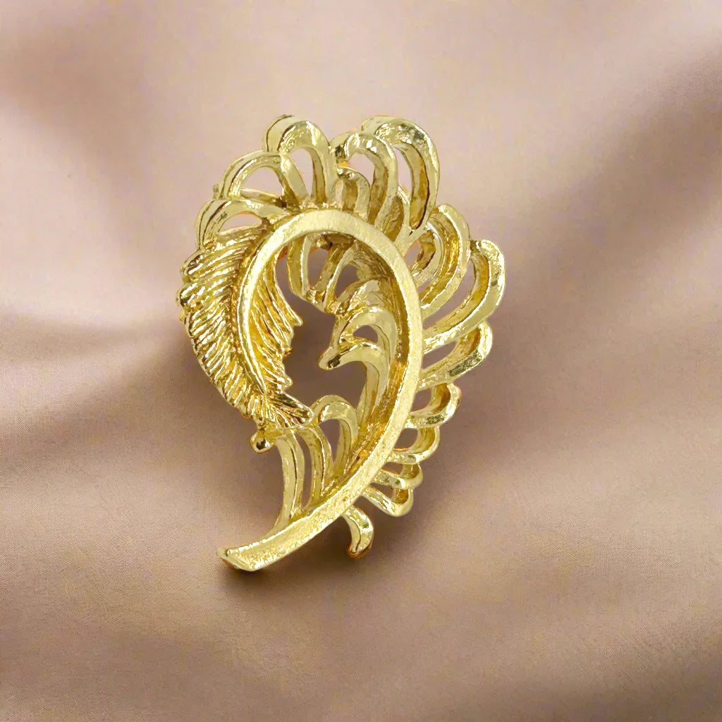 Add some vintage charm to your style with Gerry's Vintage Amusing Gold Feather Plume Brooch. The intricate openwork loops and detailed plume end make it a unique and eye-catching piece. Measuring 2" tall and 1.5" wide, it is the perfect size for any outfit.