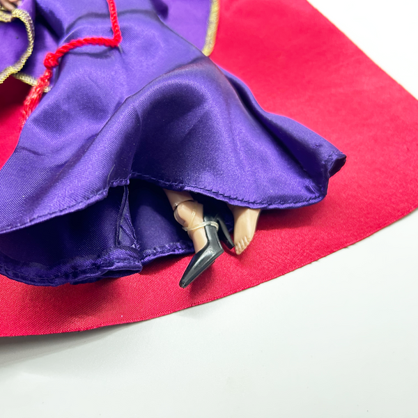 A vintage-style Evil Queen doll with a gold crown, purple gown, and red cape, photographed against a plain white background.