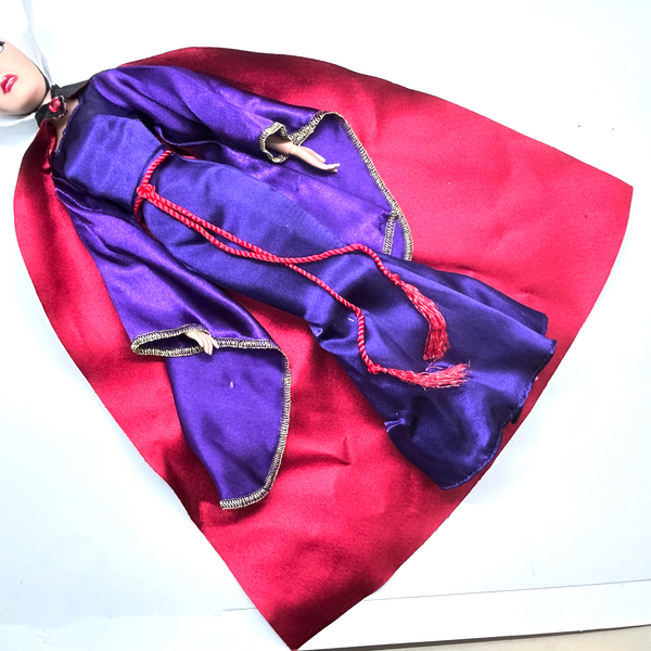 A vintage-style Evil Queen doll with a gold crown, purple gown, and red cape, photographed against a plain white background.