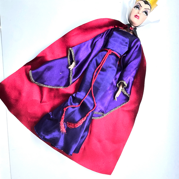 A vintage-style Evil Queen doll with a gold crown, purple gown, and red cape, photographed against a plain white background.
