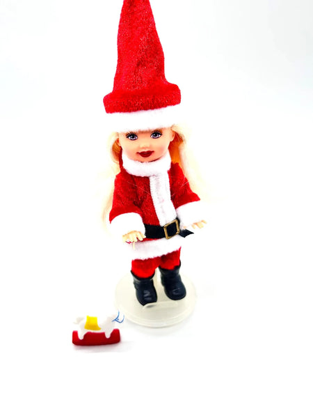The 2003 Mattel Barbie Kelly Club Santa Claus ornament doll (Model #B1347) is a 4 to 5-inch collectible fashion doll featuring&nbsp;Barbie's younger sister, Kelly, dressed in a red and white Santa-inspired outfit, complete with a long red hat, black boots, and a black belt.