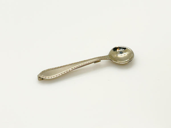 A vintage-style silver-toned metal pin with a spoon-shaped head and a long, narrow pin stem, photographed on a plain white background.