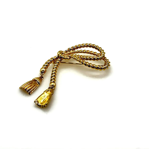 This dramatic Avon gold-tone brooch, a delightful piece from the 1980s, showcases a captivating knotted rope design. The brooch features dangling tassels, adding a touch of vintage charm.