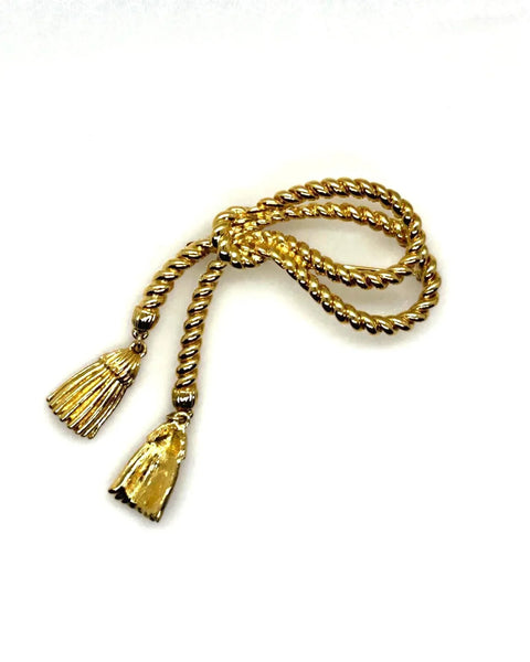 This dramatic Avon gold-tone brooch, a delightful piece from the 1980s, showcases a captivating knotted rope design. The brooch features dangling tassels, adding a touch of vintage charm.