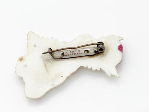 Adorable mid-century white Scottish Terrier brooch sporting a festive red plaid cap and scarf! This charming 1.75" x 1.5" plastic pup features cute brown accents on feet, ears, and face. 