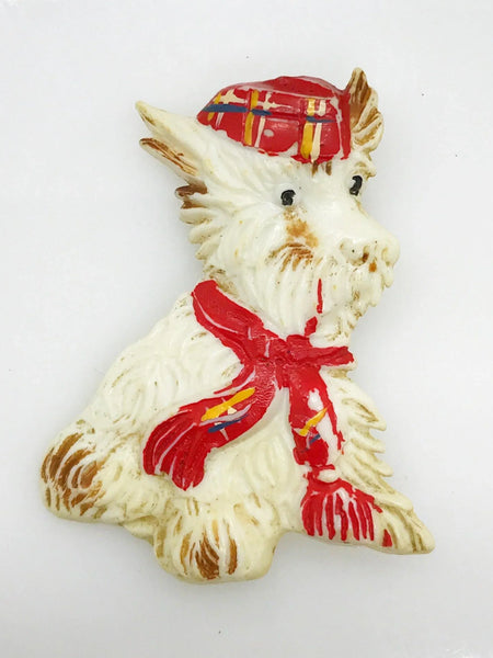 Adorable mid-century white Scottish Terrier brooch sporting a festive red plaid cap and scarf! This charming 1.75" x 1.5" plastic pup features cute brown accents on feet, ears, and face. 