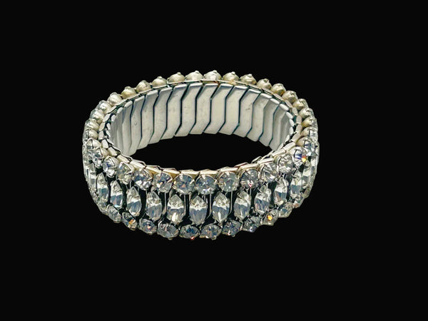 Sparkle up your vintage jewelry collection with this stunning three-row rhinestone bracelet expansion bracelet. Crafted in the classic style beloved from the 1940s through 1960s, this piece showcases brilliant clear glass rhinestones secured in a flexible silver-tone metal band. 