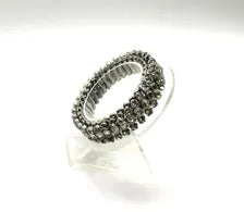 Three-row vintage rhinestone expansion bracelet with small, faceted stones set in a silvertone accordion-style stretch band, shown resting at an angle on a clear display stand against a white background