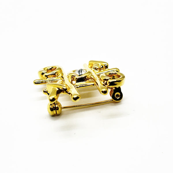 This charming Anne Klein brooch captures the playful spirit of vintage costume jewelry with its clever tic-tac-toe design. Crafted in warm gold tone, the piece features an open-style board complete with X's and O's, crowned by a sparkling clear rhinestone at its center