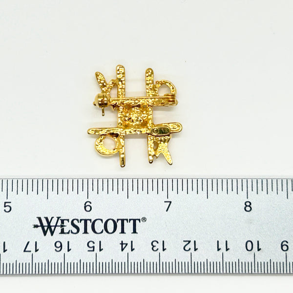 This charming Anne Klein brooch captures the playful spirit of vintage costume jewelry with its clever tic-tac-toe design. Crafted in warm gold tone, the piece features an open-style board complete with X's and O's, crowned by a sparkling clear rhinestone at its center